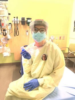 A woman wearing isolation safety gear in a hospital room