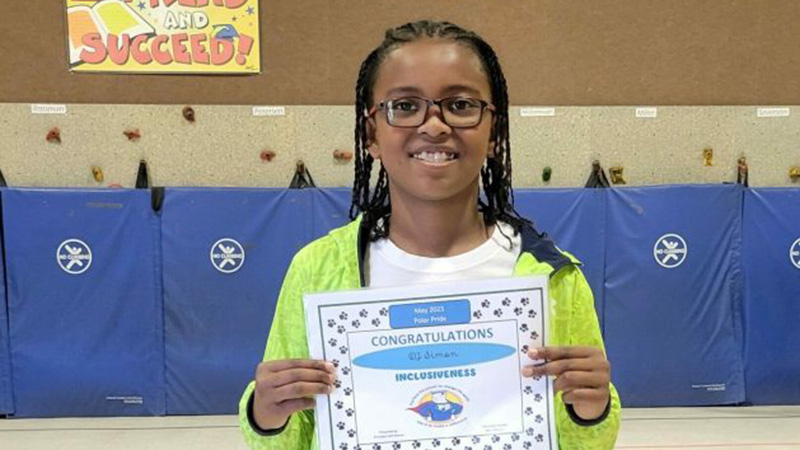 A boy in a gym holds a certificate