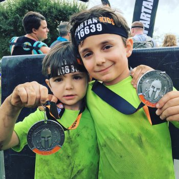 two little boys holding up medals