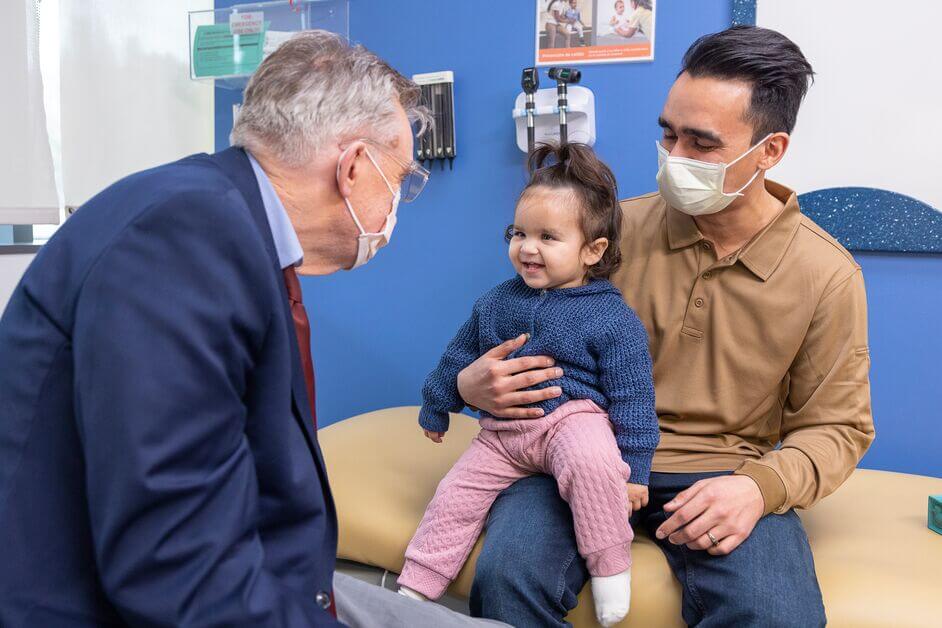 Dr. Edward Novotny interacting with a child and caregiver