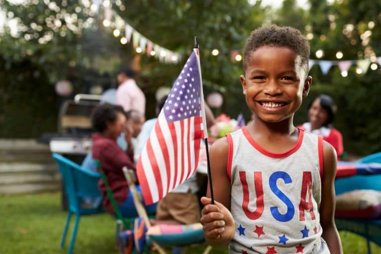 A boy celebrates the fourth of July holding a flag.