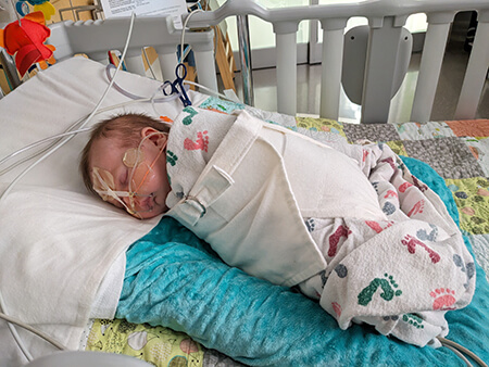 A swaddled baby in a hospital bed