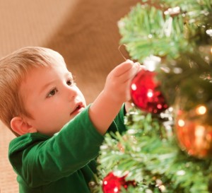 A child hangs an ornament on a tree.