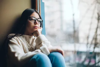 A teenage girl looks out a window