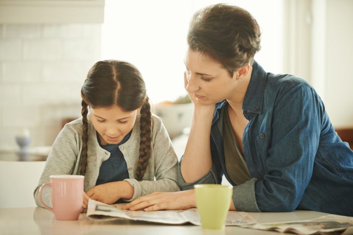 A family reads a newspaper together.