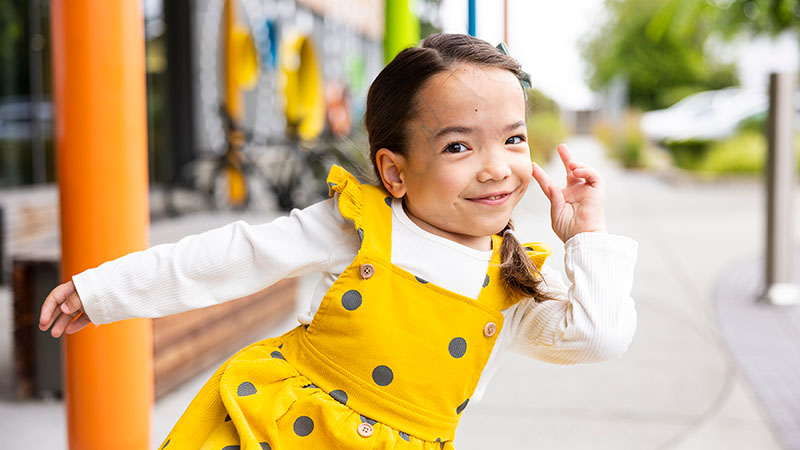 A girl in a yellow dress poses outside