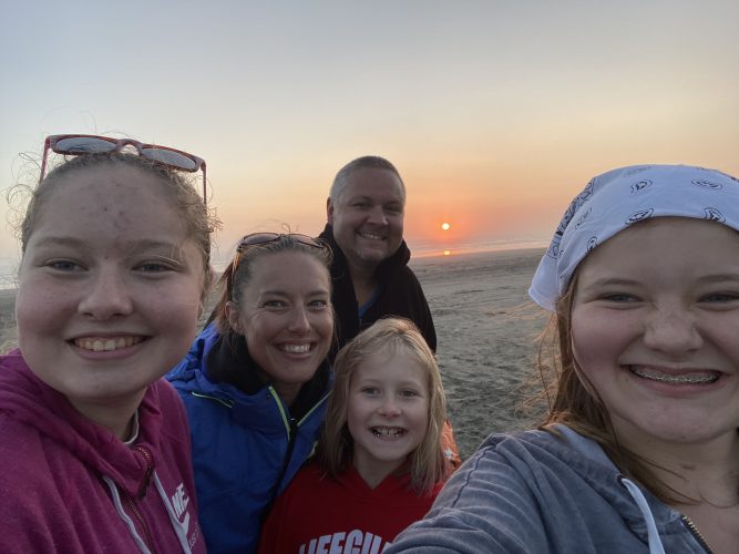 The Caveness family poses at sunset on a beach.