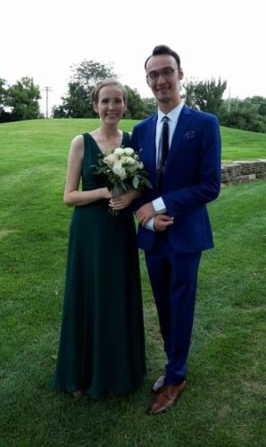 A teen girl and a teen boy posing in prom clothes