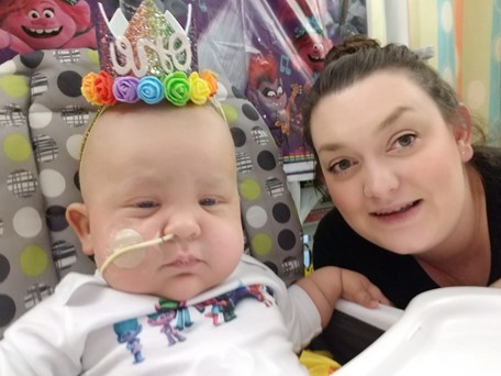 mom posing with her daughter on her first birthday