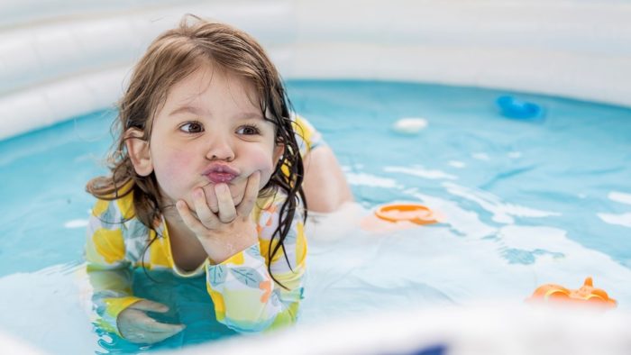 a little girl in her swim outfit in a small pool