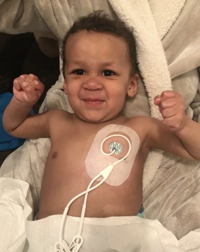 A toddler holds up his arms showing how strong he is