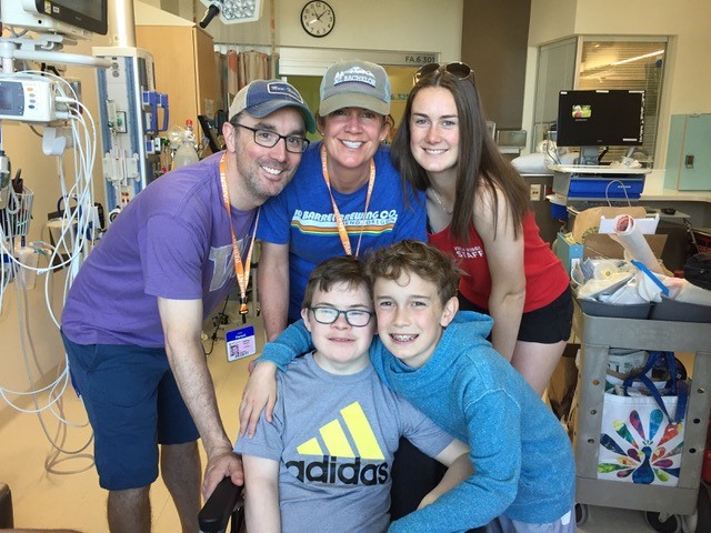 Family poses with son in hospital room