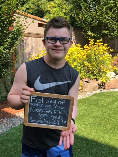 a male teen holds up a first day of school chalkboard sign