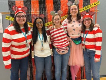 A group of woman in coordinated red and white outfits pose by a photo background