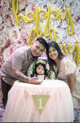 Parents posing with their baby at the baby's first birthday