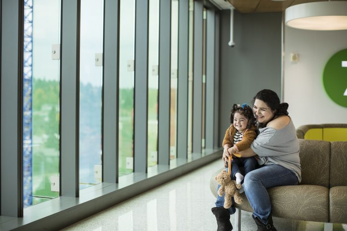 A mother cuddles her little girl while sitting in a hospital waiting area