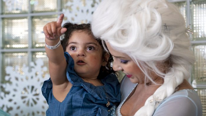 A little girl points while in the arms of a princess in a Frozen costume