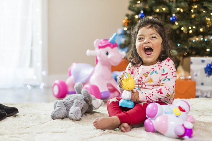 A little girl giggles under a Christmas tree