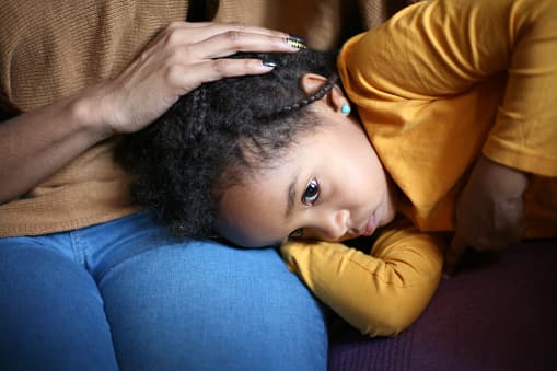 Child with a stomachache takes comfort in their parents lap.