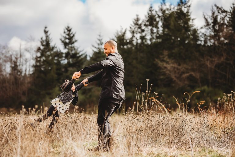 A father swinging his daughter by the arms in a field