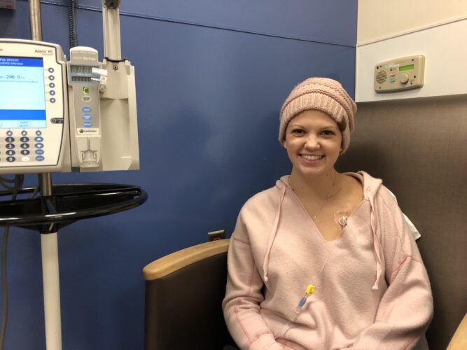 A teen girl sits in a chair while hooked up to receive chemotherapy