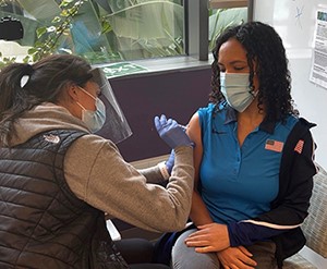 A nurse gives a woman a vaccine in her arm