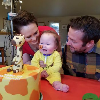 a mom and dad fawn over their son as he smiles looking at his birthday cake