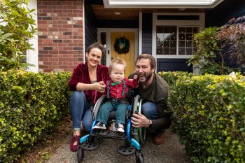 a family smiles in front of their home