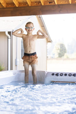 A boy stands in a hot tub