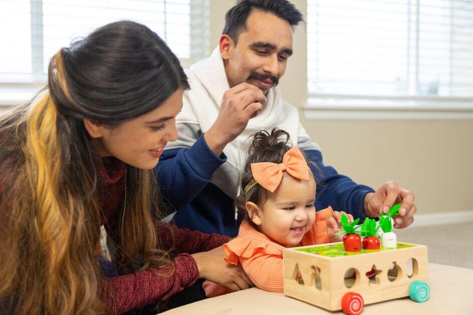 A girl plays with her parents at home.