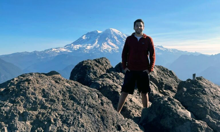 A young man stands on a mountain