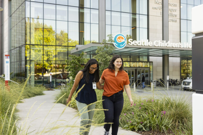 A young woman walks with her doctor outside Seattle Children's