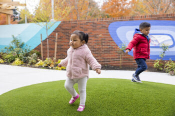 Two kids play outside in winter coats