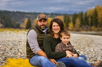 A family sits on a river bank together