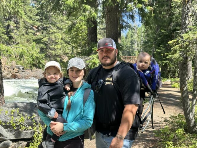 a family smiling and posing for a photo while on a hike in the woods