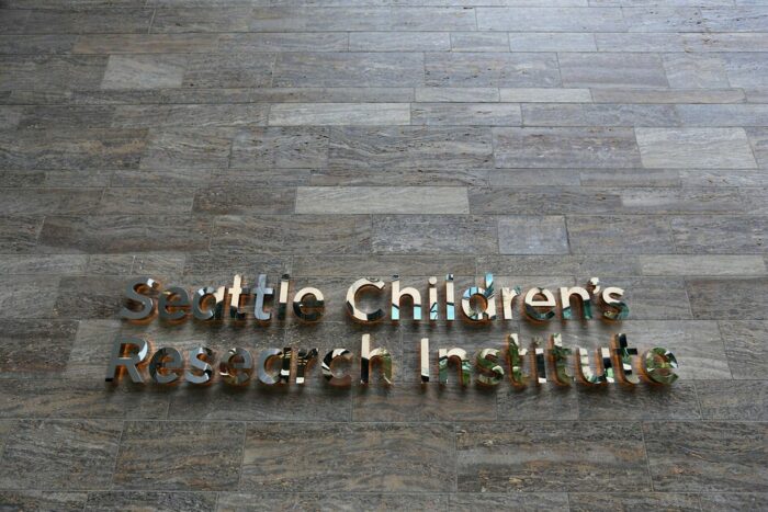 Mirrored signage that says, "Seattle Children's Research Institute," on a tiled wall 