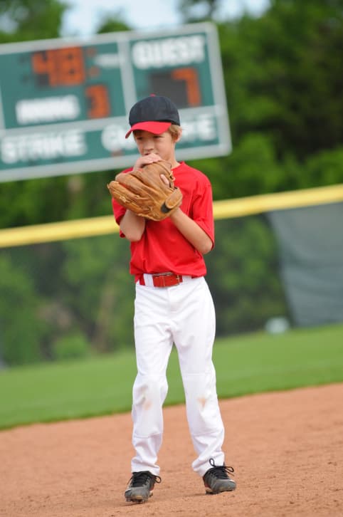 A young boy winds up for a baseball pitch.