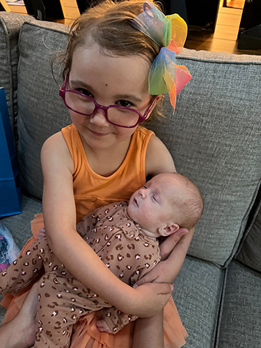 A young girl holds her newborn sibling