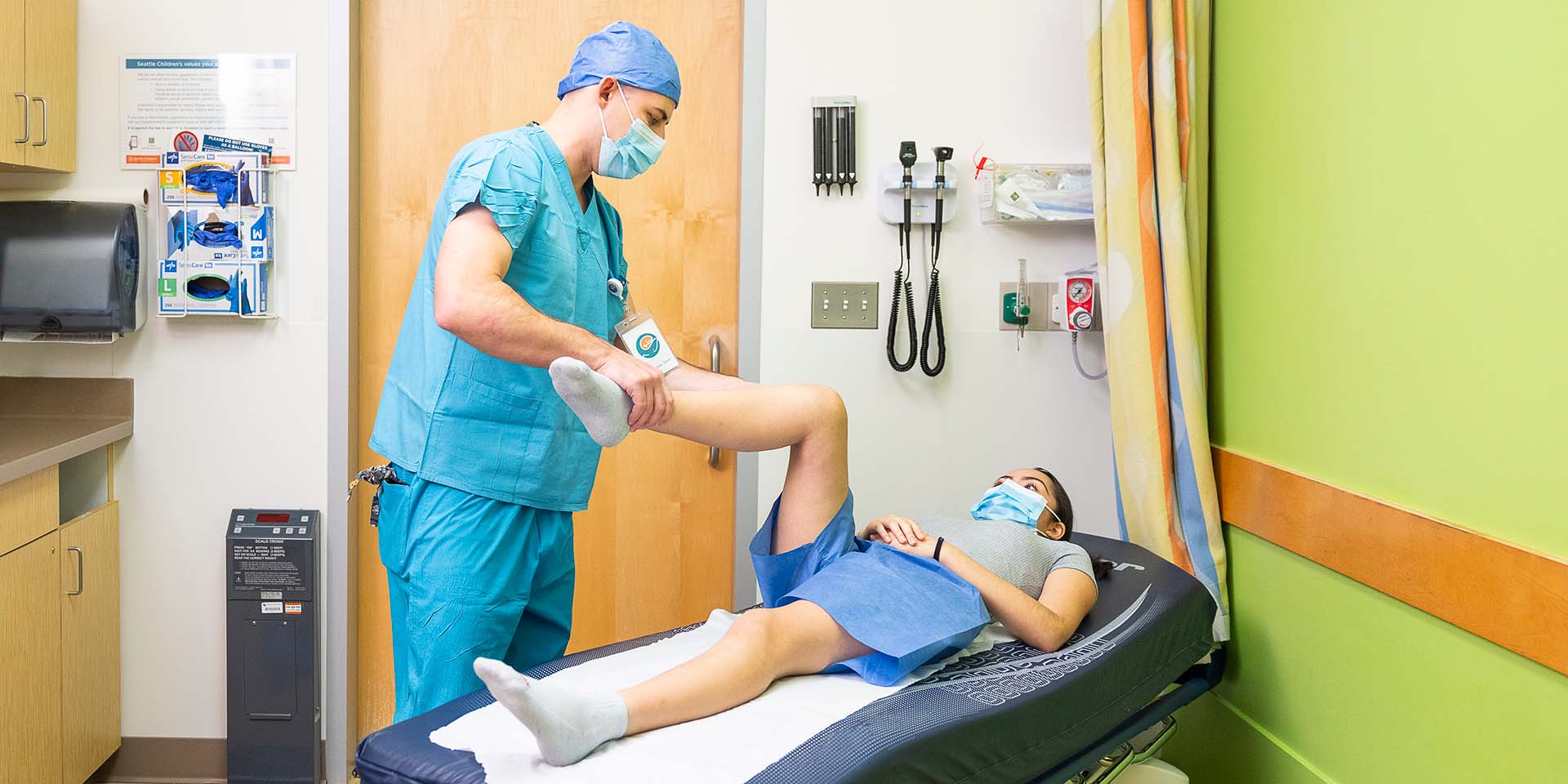 A surgeon tests the flexibility of a child patient's leg.