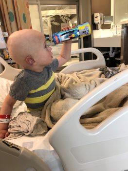 a boy is looking through a telescope while in his hospital room