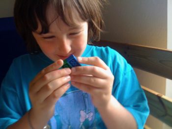 A woman examines two green and blue Lego blocks