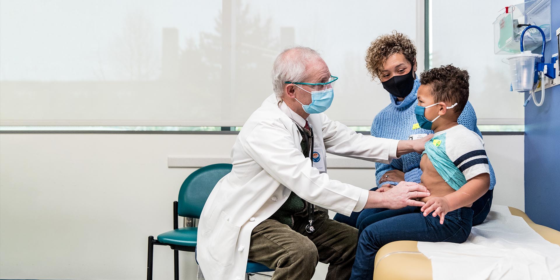 A doctor examines a young patient and their mothers watches