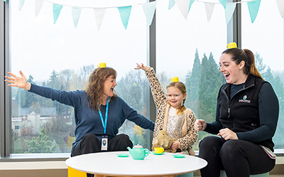 A patient and two of her care team members pose with party hats celebrating a care milestone