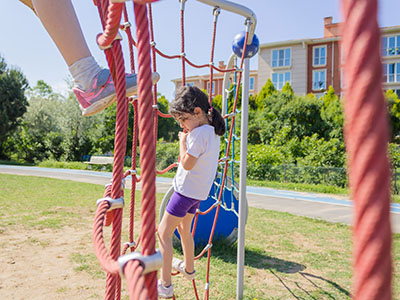 A girls climbs a rope wall in the summer