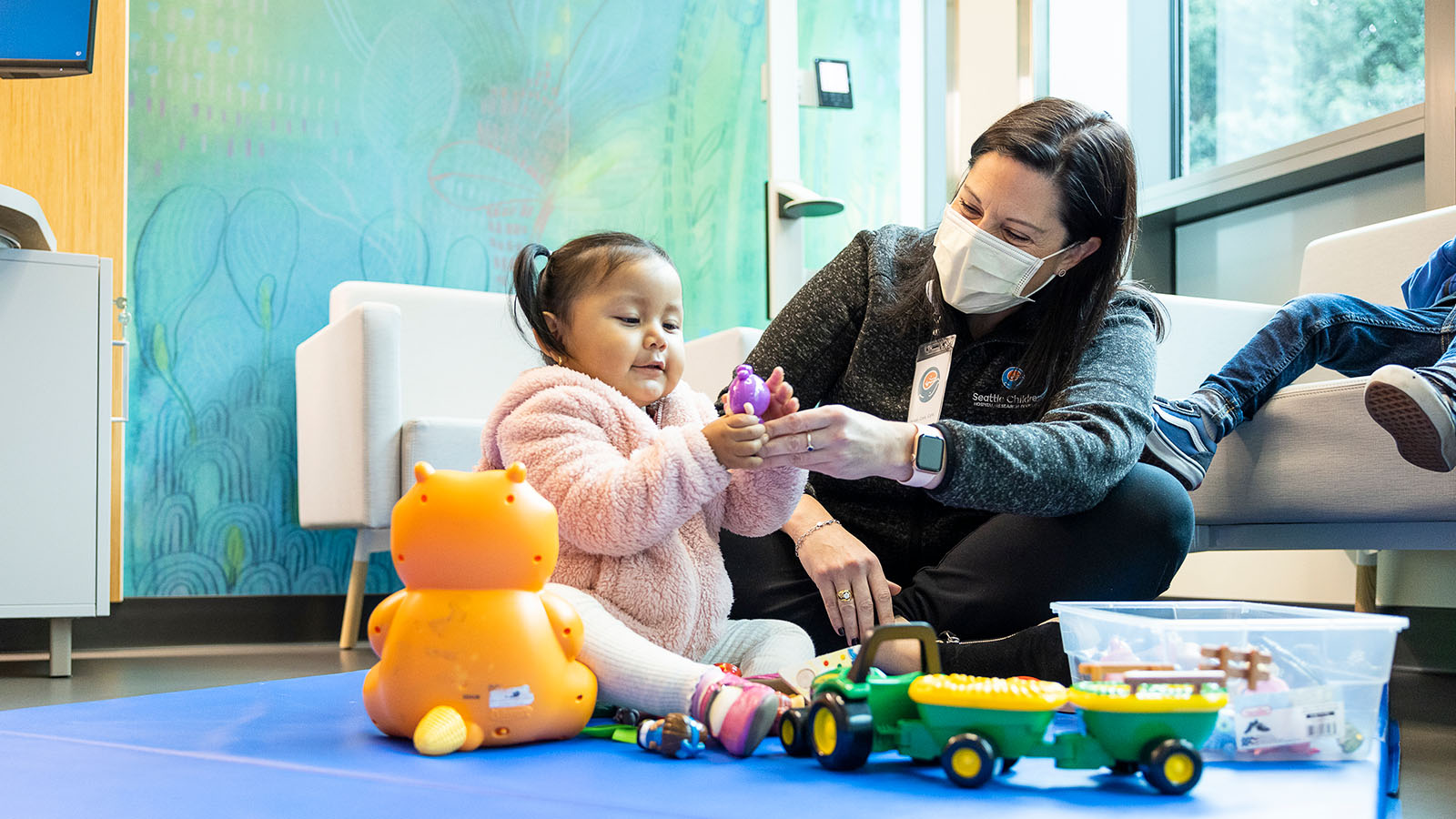 A Seattle Childre's providers hands a toy to a toddler