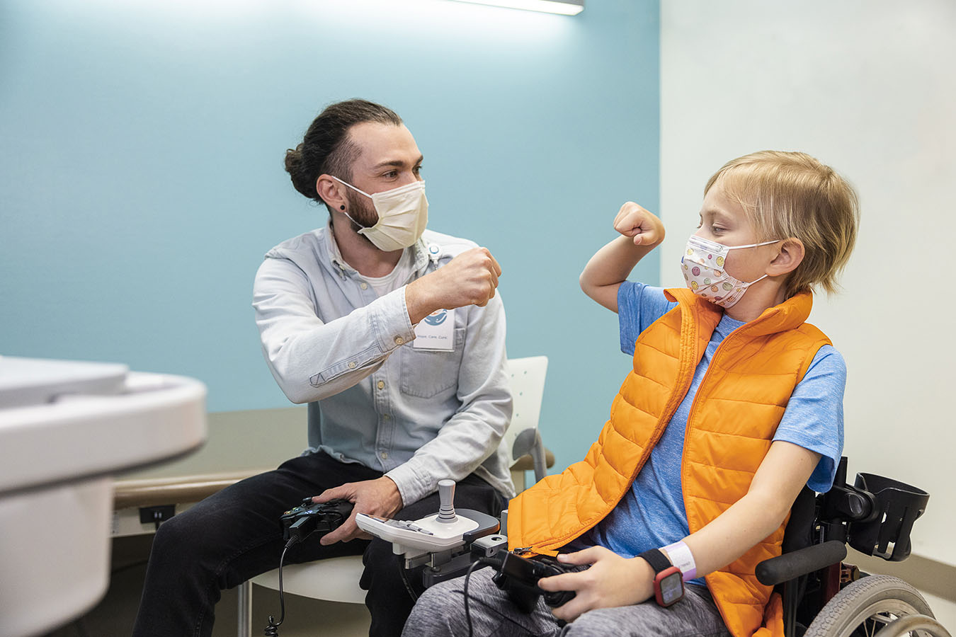 Hudson, Heart Center patient, and Forest Coyle, Therapeutic Gaming Specialist, fist bump while playing a game.​