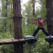 A boy walking on zipline platforms in a forest