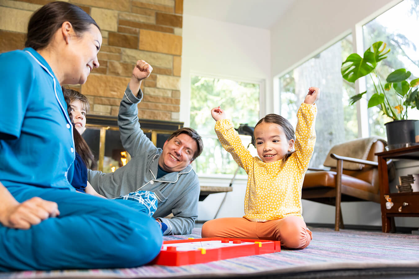 A girl playing a board game on the living room floor with her family