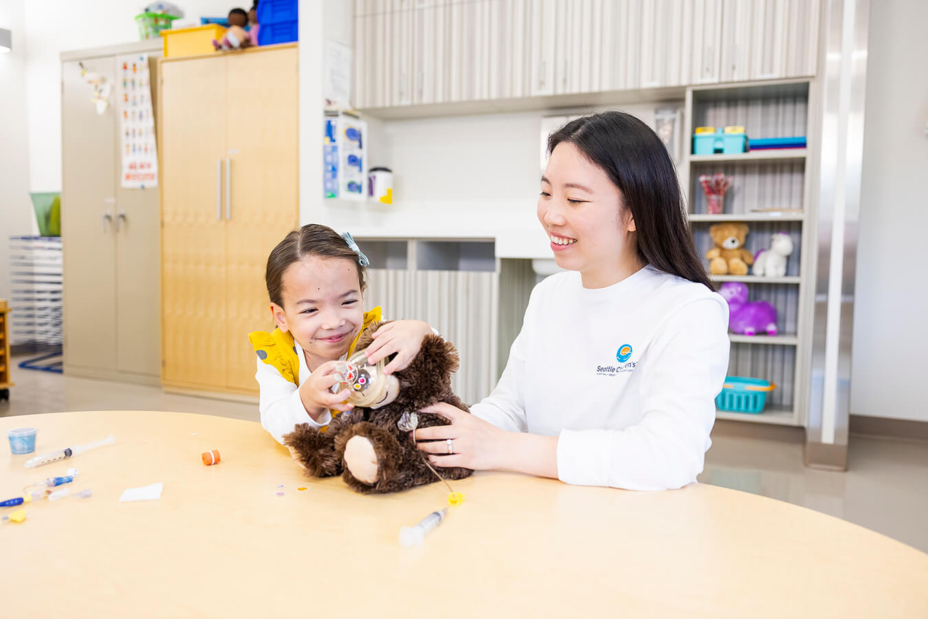 A girl, medical provider, and teddy bear