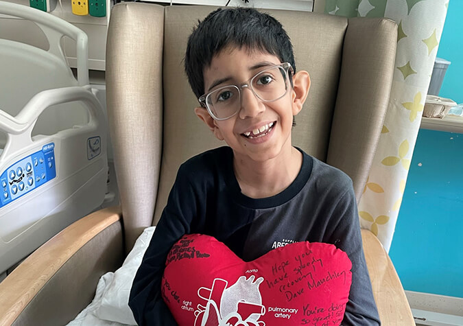 Child sitting in chair holding heart stuffie